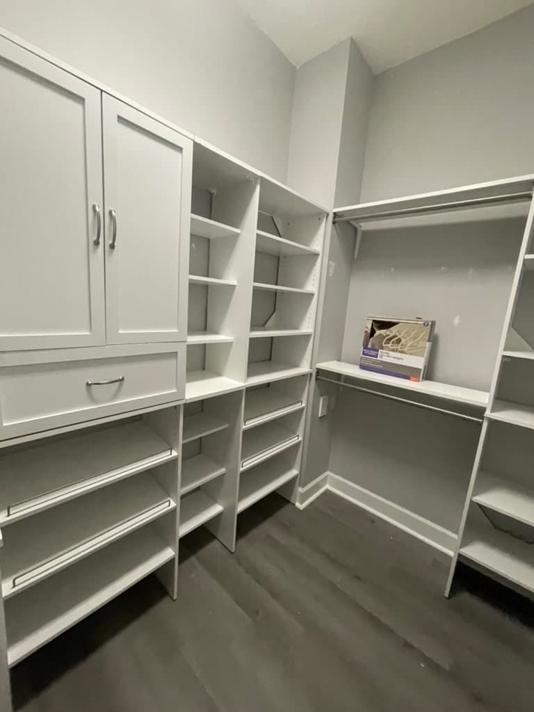 Walk-in closet with white shelving and gray plank flooring