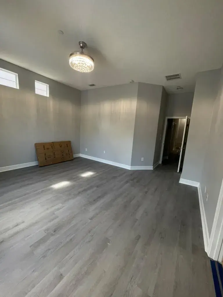 Large room with new gray plank flooring and white baseboards