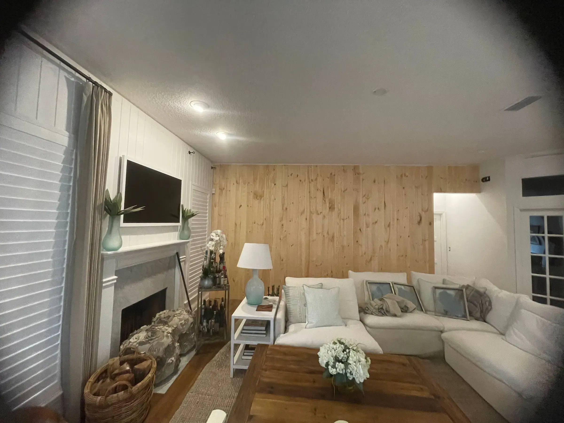 Living room with a natural wood-paneled wall, a white paneled fireplace wall and a sectional sofa