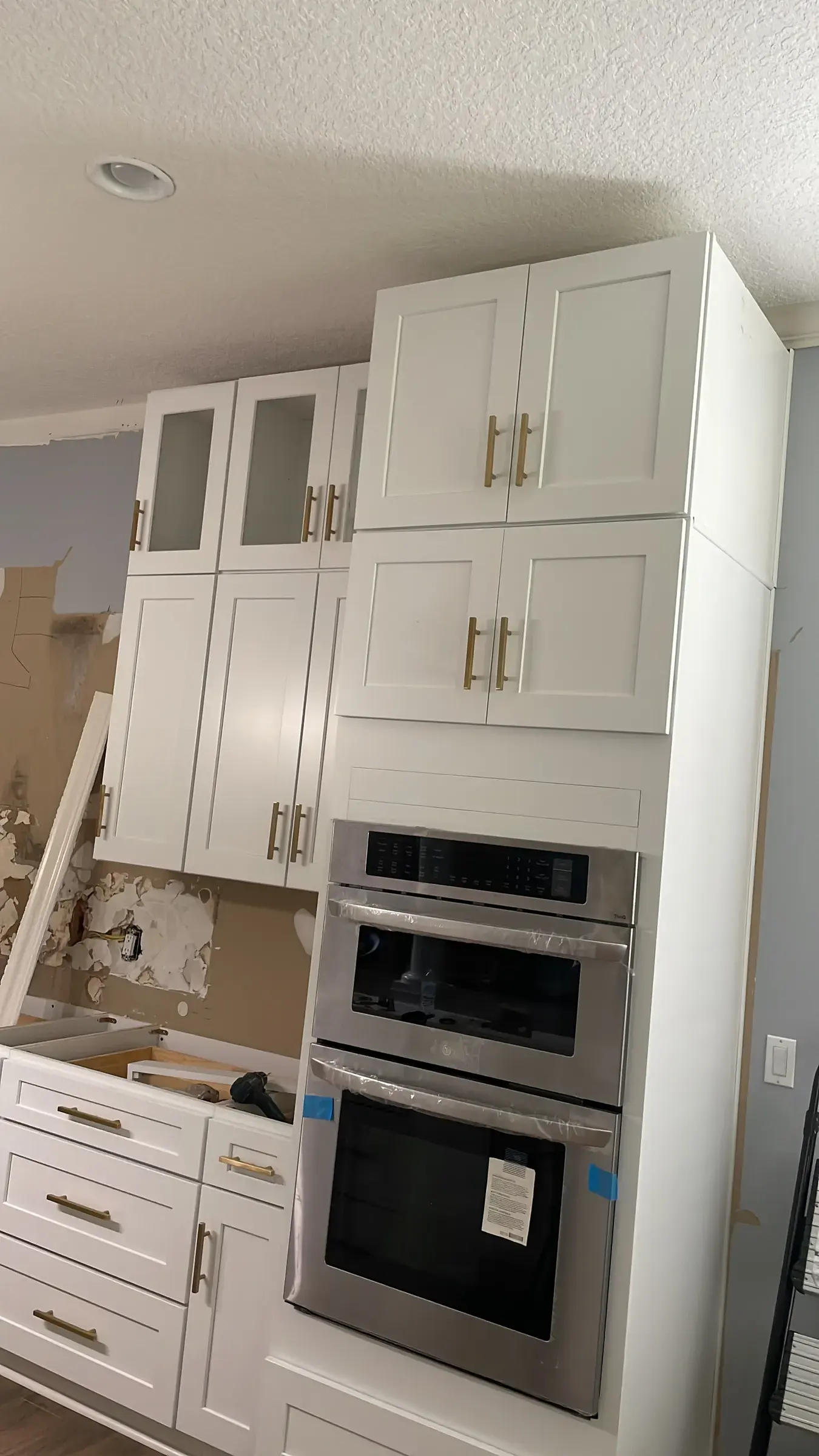 White cabinet tower with a double wall oven and white upper cabinets during installation