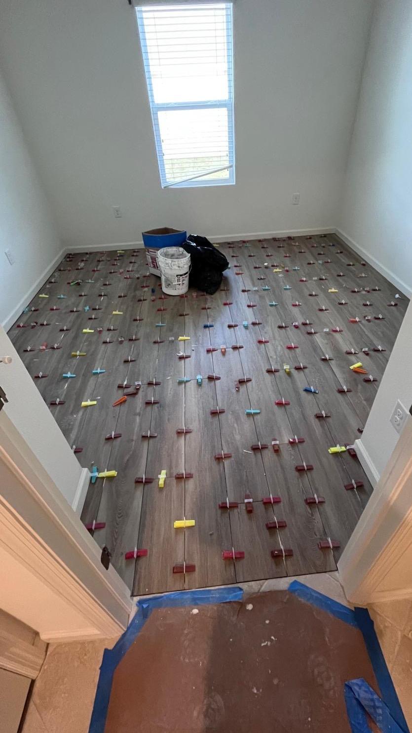 The same small room during installation, with leveling clips across the new flooring