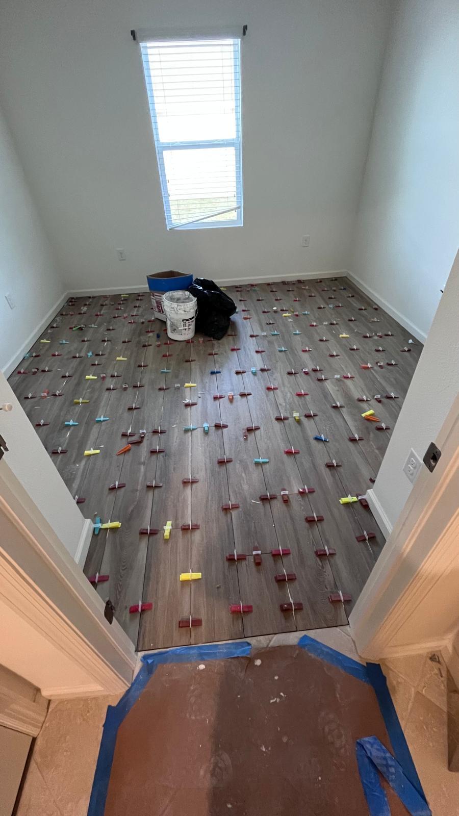 The same small room during installation, with leveling clips across the new flooring