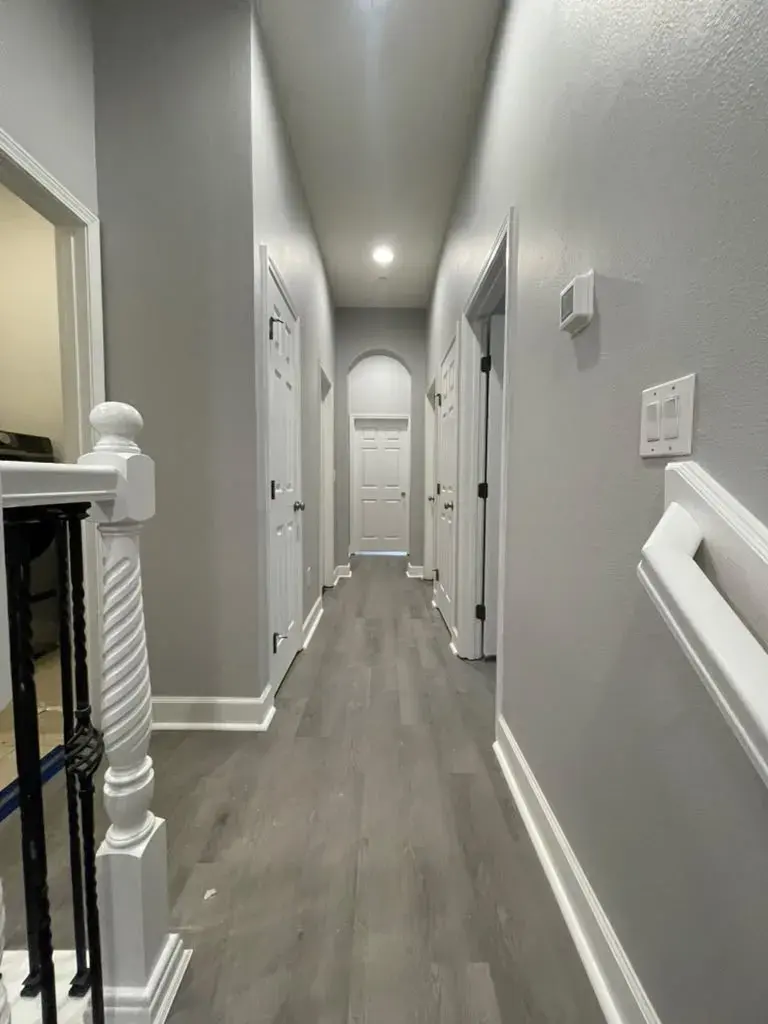 Hallway with continuous gray plank flooring and white baseboards