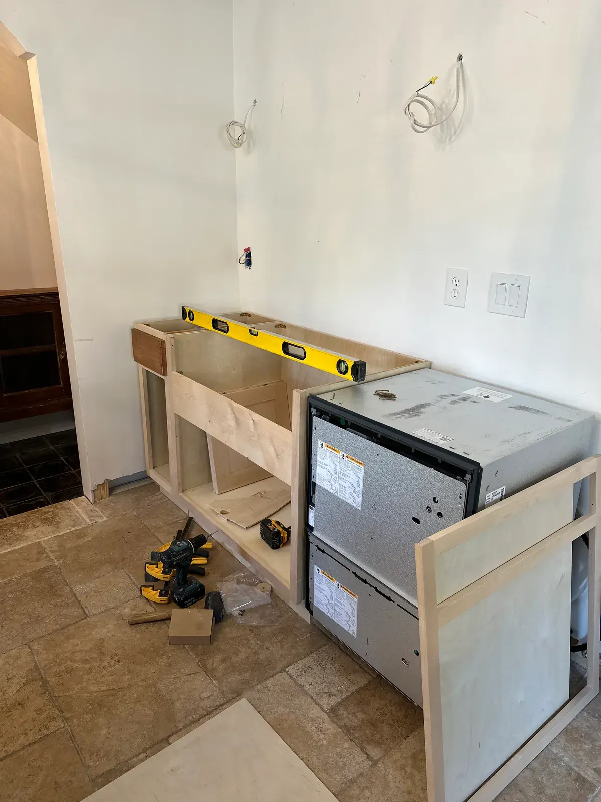 Base cabinets being installed, with a level on top and tools on the floor